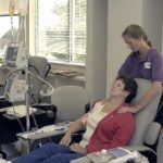 Woman leaning back in chair in chemo infusion room getting shoulder massage